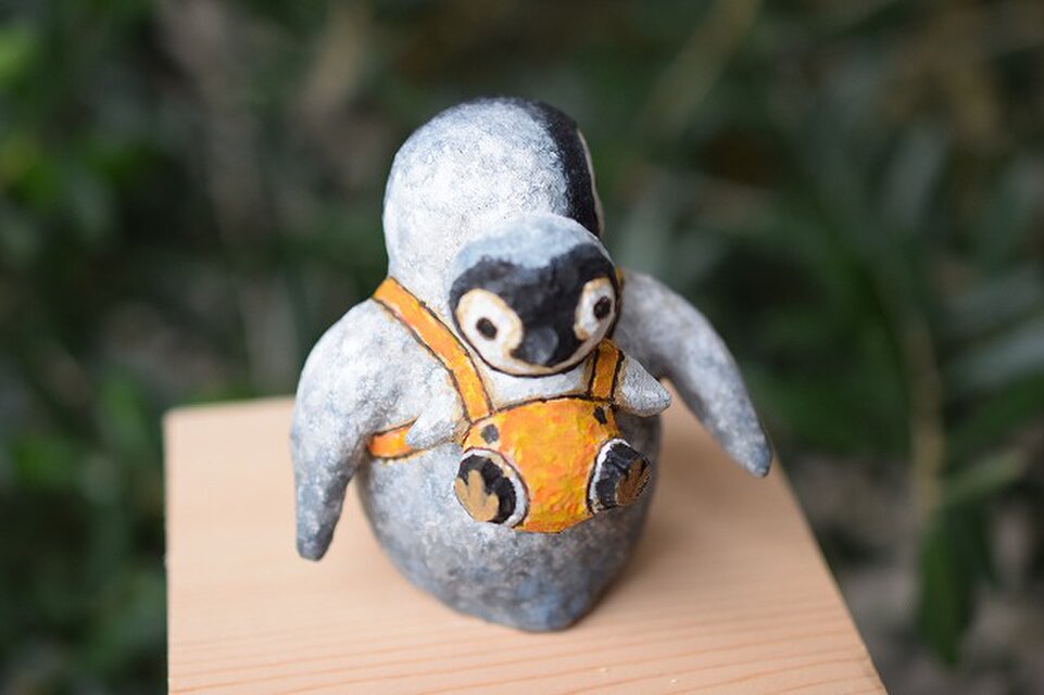 皇帝ペンギンの赤ちゃん人形をおんぶする皇帝ペンギンの赤ちゃん
