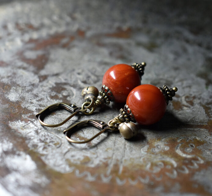 珊瑚色まん丸アフリカンアンバーと民族鈴のピアス(1.2ｍｍ)