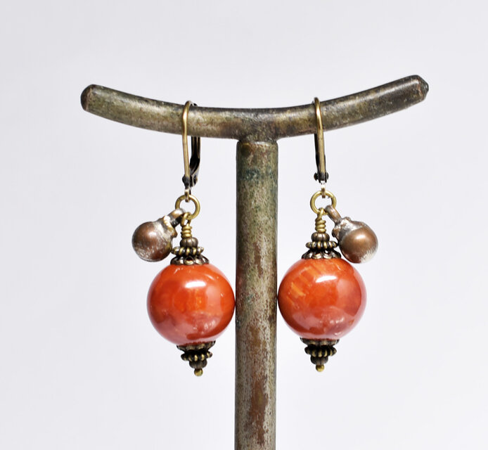 珊瑚色まん丸アフリカンアンバーと民族鈴のピアス(1.4mm) | iichi