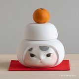 ブチ猫　鏡餅（かがみもち）のかぶりものをした猫の置物　陶土・陶器の画像