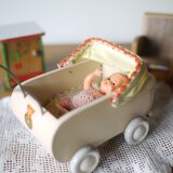 木製ベビーカーとピンクのベビー服の女の子