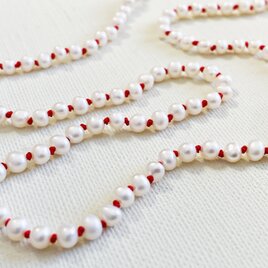 赤い糸と白いパールのシンプルなショートネックレスの画像