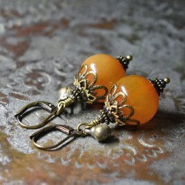 まん丸艶やかなアフリカンアンバーと民族鈴のピアス（淡）