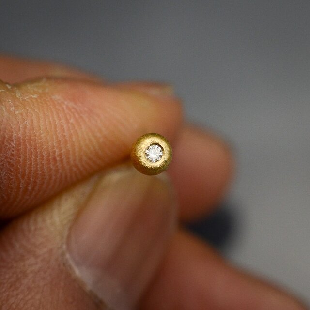 ダイヤモンドをコロンとした22カラットゴールドのシャカ玉に埋め込んだプチピアスの画像1枚目