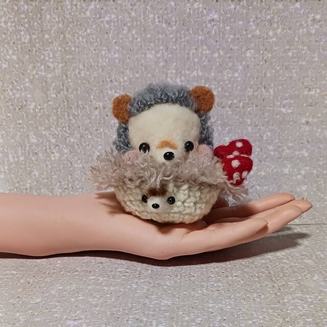 ハリネズミちゃんがハリネズミ手編み容器に乗っています。
