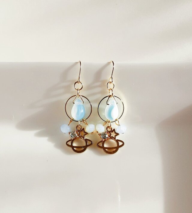 土星チャームとサークルフープのマーブルライトブルーカラーのピアス