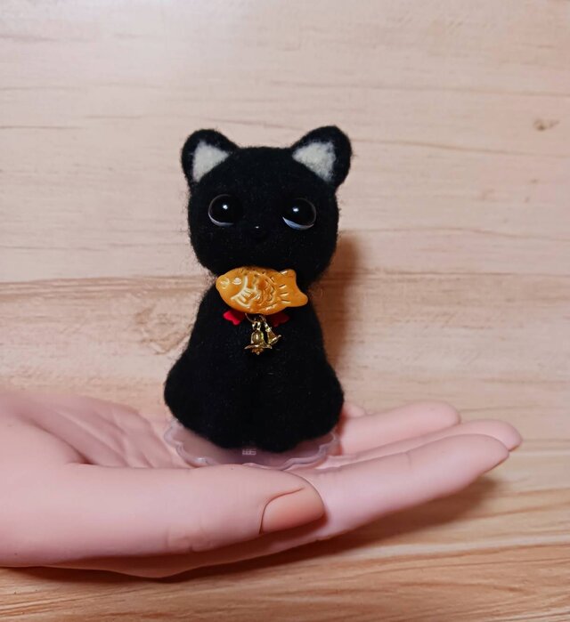 小さくて目のクリクリの可愛い黒猫 口にくわえてるのタイ焼きだよ